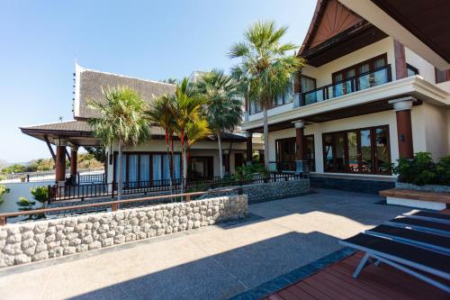 a house with palm trees and a stone wall at Grand View Panwa Luxury Villa in Ban Ao Makham