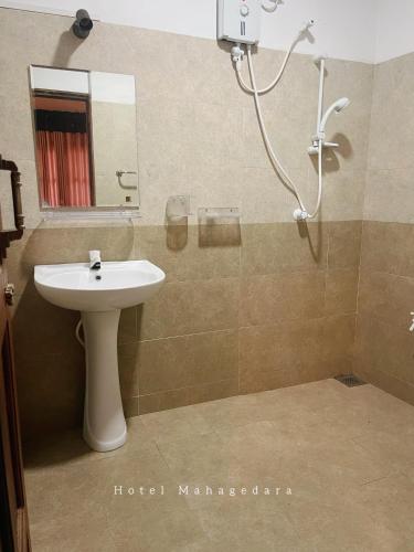 a bathroom with a sink and a shower with a mirror at Hotel Mahagedara in Anuradhapura