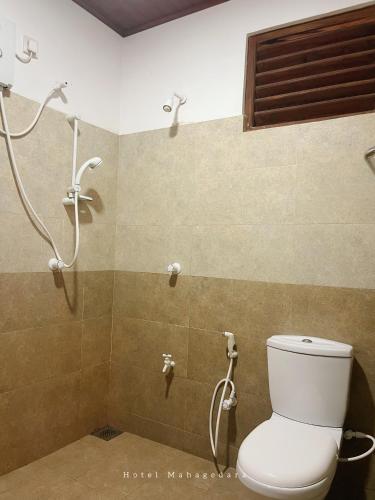 a bathroom with a toilet and a shower at Hotel Mahagedara in Anuradhapura