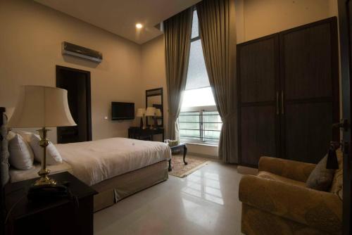 a bedroom with a bed and a couch and a window at Cozy Guest Room F-7 Markaz Islamabad in Islamabad
