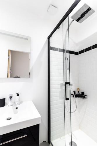 une salle de bain blanche avec une douche et un lavabo dans l'établissement LE COCON DORE Hyper-centre & Cozy - WIFI, à Toulouse