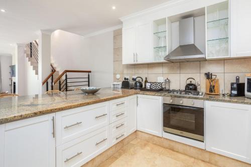 a kitchen with white cabinets and marble counter tops at Luxury Lodge 4C, Pearl Valley Golf Course in Paarl