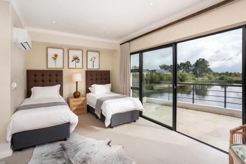 two beds in a bedroom with a large window at Luxury Lodge 4C, Pearl Valley Golf Course in Paarl