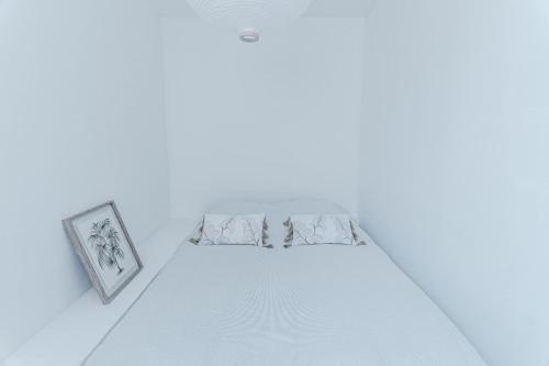 Ce lit se trouve dans une chambre blanche avec 2 photos encadrées. dans l'établissement Superbe 2 Pièces - Viel Antibes, à Antibes