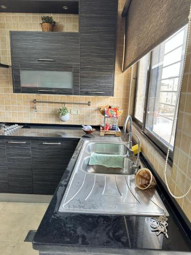a kitchen with a stainless steel sink and black cabinets at shafa badran شفا بدران ام الحجير in Amman