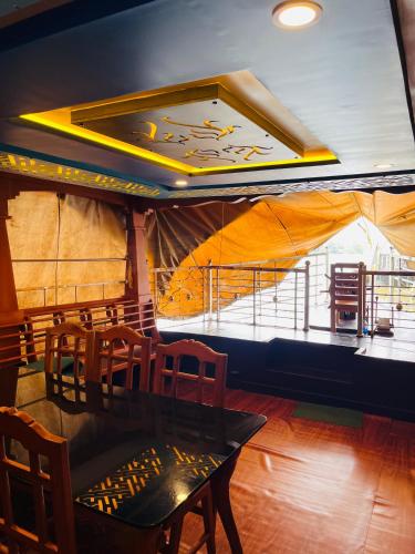 Un comedor con mesa y sillas y una gran ventana. en sajiholidays houseboats, en Alleppey