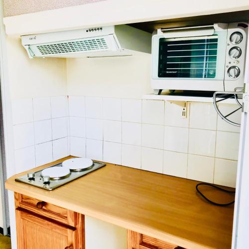 une cuisine avec une cuisinière et un micro-ondes dans l'établissement Soleil d'Or - Appartement curistes balcon - terrasse, à Lamalou-les-Bains