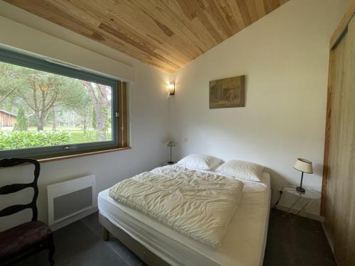 un lit dans une chambre avec une grande fenêtre dans l'établissement Villa 4 pers. avec jardin privé, animaux acceptés, tout confort à Messanges - FR-1-379-136, à Messanges
