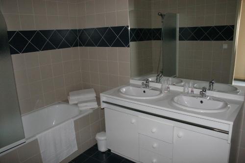 une salle de bain avec deux lavabos, une baignoire et un miroir dans l'établissement La résidence des bains forts, à Rennes-les-Bains