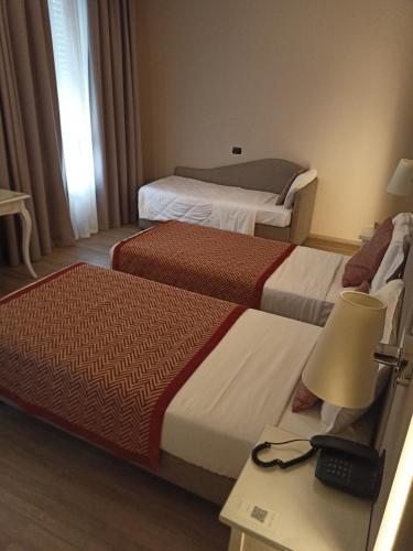 a hotel room with two beds and a table with a lamp at Hotel Villa Malpensa in Vizzola Ticino
