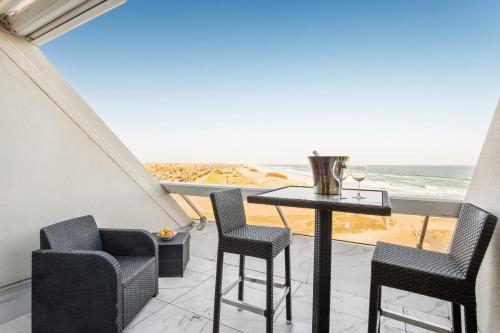 - un balcon avec une table et des chaises et la plage dans l'établissement Sea Life Heliopolis, au Cap d'Agde