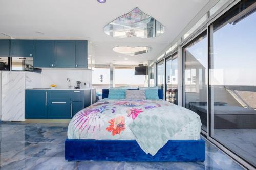 Cet appartement comprend une chambre avec un lit et une cuisine avec des placards bleus. dans l'établissement Elixir Heliopolis, au Cap d'Agde