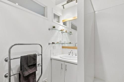 a white bathroom with a sink and a mirror at Miranda Oasis in Torquay