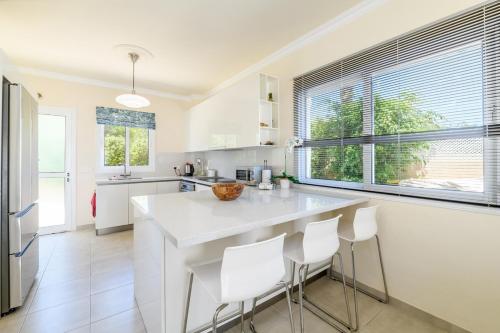 a kitchen with a large white island with white chairs at Protaras Holiday Villa - Katia 8B in Protaras