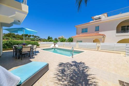 a patio with a table and chairs and a swimming pool at Protaras Holiday Villa - Katia 8B in Protaras