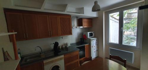 une cuisine avec des armoires en bois, un évier et une fenêtre dans l'établissement Le long de la rivière, à Biriatou