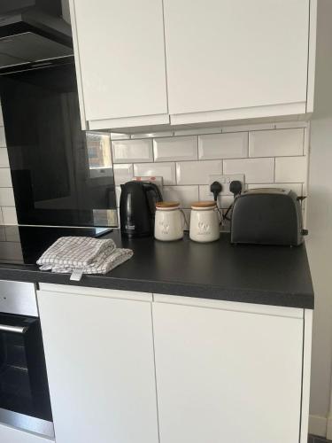 a kitchen with white cabinets and a black counter top at Brigadoon House Lochgilphead in Lochgilphead