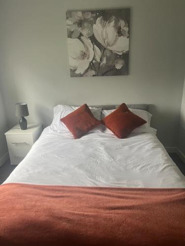 a white bed with two red pillows on it at Brigadoon House Lochgilphead in Lochgilphead