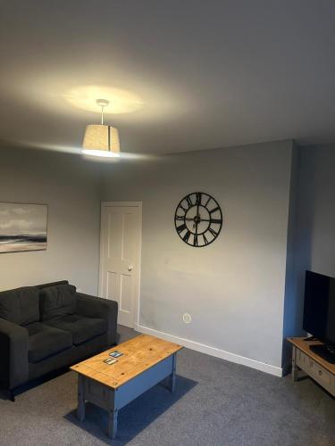 a living room with a couch and a clock on the wall at Brigadoon House Lochgilphead in Lochgilphead