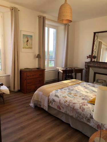 a bedroom with a bed and a dresser and a mirror at l'appart de la Maison du Hommeel in Gratot