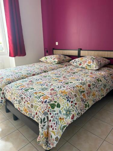 - une chambre avec 2 lits et un mur violet dans l'établissement Pierres d'estuaire, à Valeyrac