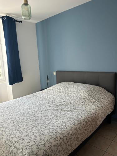 Ce lit se trouve dans une chambre dotée d'un mur bleu. dans l'établissement Pierres d'estuaire, à Valeyrac