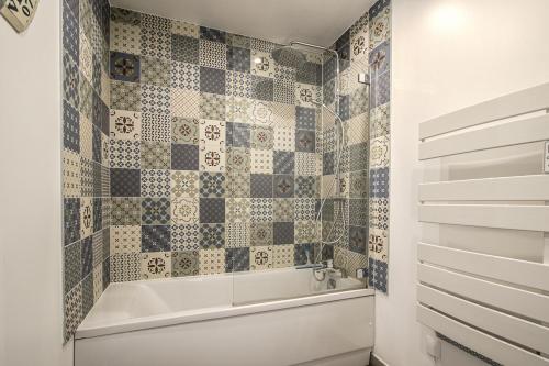 La salle de bains est pourvue d'une baignoire et d'un mur carrelé. dans l'établissement La cabane de plage, à Étretat