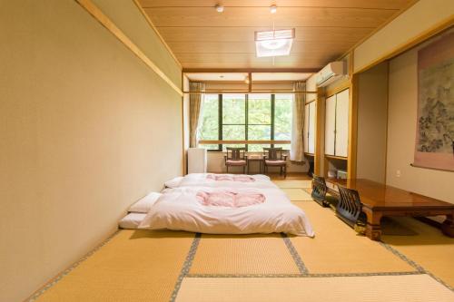 a bedroom with a bed and a table in it at Akasawa Onsen Ryokan in Nasushiobara