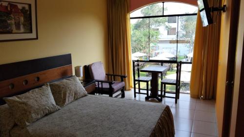 a bedroom with a bed and a table and a balcony at Tambo II Hotel Campestre in Cieneguilla