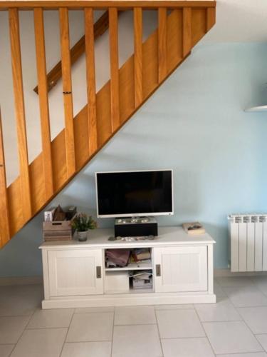 - un salon avec une télévision dans une armoire située sous un escalier dans l'établissement Appartement face à la mer, à Guidel