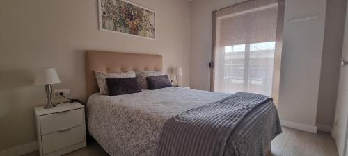 a white bedroom with a bed and a window at Apartamentos Neptuno in Platja  d'Aro
