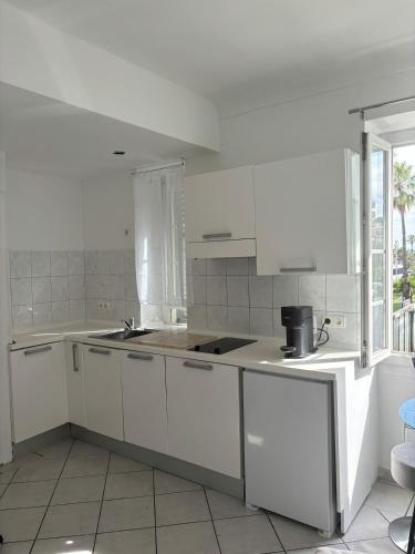 une cuisine blanche avec des armoires blanches et un évier dans l'établissement Cozy studio sur la promenade, à Nice
