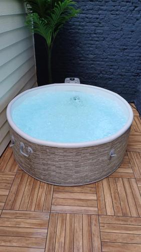 a large bath tub sitting on a wooden floor at Le Bleu OMER - Jacuzzi & Netflix - Terrasse privée I Coeur de ville & Transports - Idéal FAMILLE - OFFRE SPÉCIALE in Saint-Omer