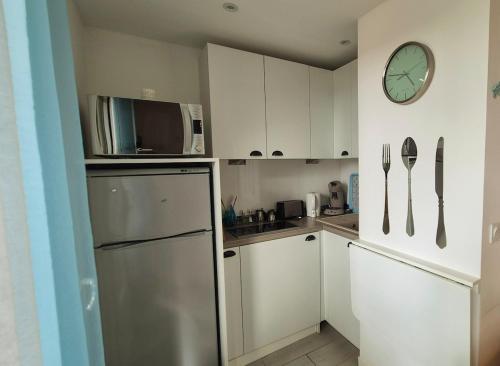 Il comprend une cuisine équipée d'un réfrigérateur et d'une horloge murale. dans l'établissement Bohème Chic en bord de plage, à Argelès-sur-Mer