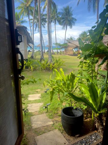 a door to a yard with a tire in the grass at Eco Sanctuaries Nature Lodge Nacpan Beach, El Nido in El Nido