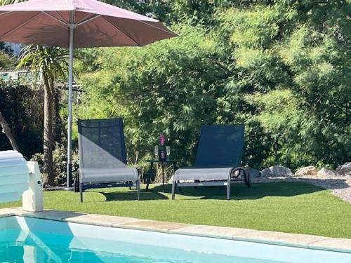 two chairs and an umbrella next to a swimming pool at Villa La Liberté in Arles-sur-Tech