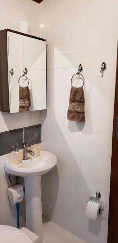 a white bathroom with a sink and a mirror at Pousada Recanto da Pantera in Cunha