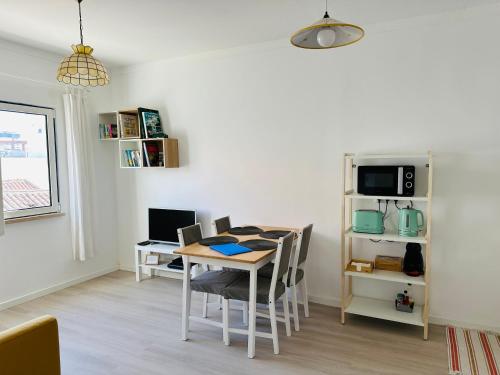 a dining room with a table and chairs and a tv at Casa do Viajante - Family in Zambujeira do Mar