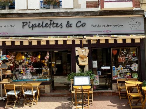 a store with tables and chairs in front of a store at Trouville Palace Le Bonheur in Trouville-sur-Mer