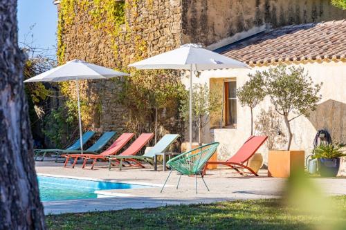 - un groupe de chaises longues et de parasols à côté de la piscine dans l'établissement Le mas des vignes, à Rochegude