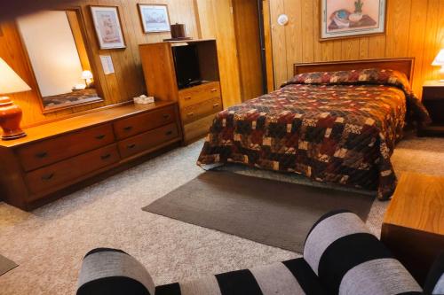 a bedroom with a bed and a dresser and a tv at Love Hotels Voyageur by OYO at International Falls MN in International Falls