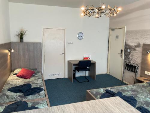a room with two beds and a desk and a table at Hotel Poseidon in Scheveningen