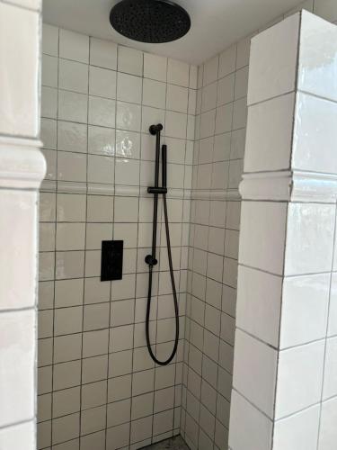 a shower with a hose in a white tiled bathroom at Beautiful entire house in the center in Medemblik