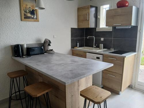 a kitchen with a counter and two stools in it at Jolie appartement refait à neuf in Saintes-Maries-de-la-Mer