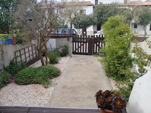 a garden with a wooden fence and a walkway at Jolie appartement refait à neuf in Saintes-Maries-de-la-Mer