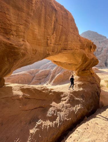 a person standing under a rock in the desert at Bedouin Life Camp in Aqaba