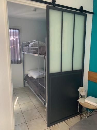 Cette chambre dispose de lits superposés et d'une porte. dans l'établissement Rce les Coraux, cosy T1, situé à 7' à pied de la plage et du centre, clim, wifi, parking privé, piscines, à Canet