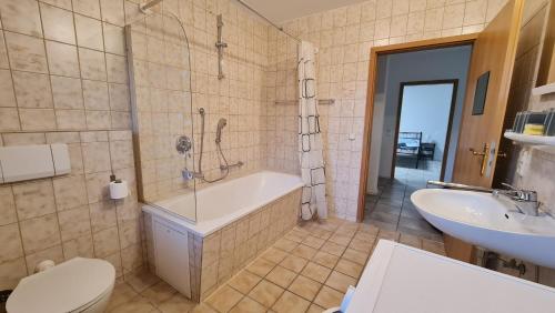 a bathroom with a tub and a toilet and a sink at Gästehaus Wohnung #3 in Jülich