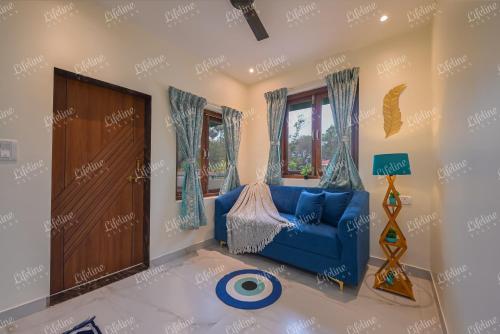 a living room with a blue couch and windows at Sea Shell By The Sea Luxurious Villa 3min From Awas Beach Surrounded By Mango Trees in Alibaug