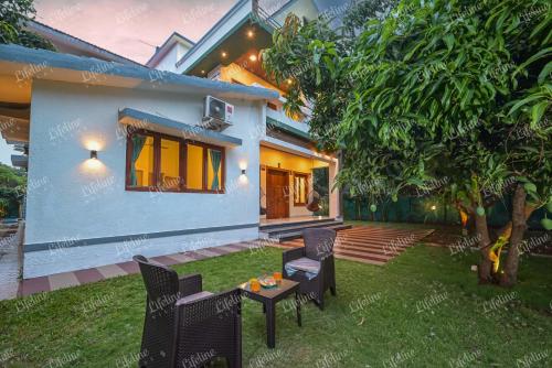a house with a yard with chairs and a table at Sea Shell By The Sea Luxurious Villa 3min From Awas Beach Surrounded By Mango Trees in Alibaug